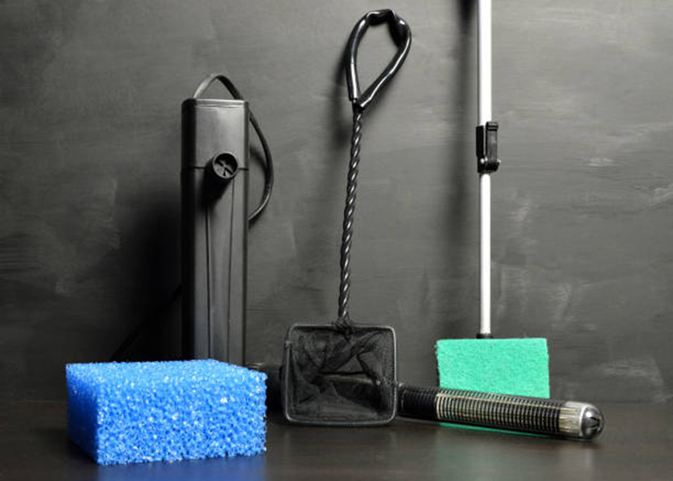 Aquarium maintenance equipment and gear laying on a black table with a black background.