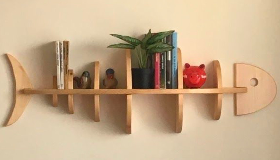 Fish bone shaped wall mounted shelving with books, a plant and other items on the shelves.